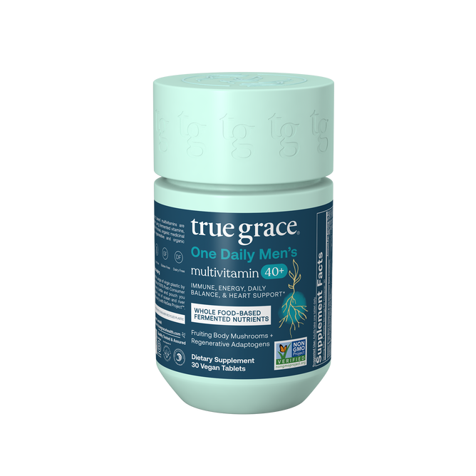 A teal bottle of True Grace One Daily Mens 40+ Multivitamin with labels highlighting immune, energy, heart support, daily balance, vegan tablets, whole food-based nutrients, chelated minerals, and non-GMO certification.