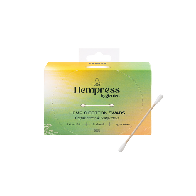 A box of Hempress Hygienics Hemp Swabs, featuring organic cotton, hemp extract, eco-friendly labeling, and enriched with hemp seed oil. Vegan-friendly; one swab is positioned diagonally in front of the box.