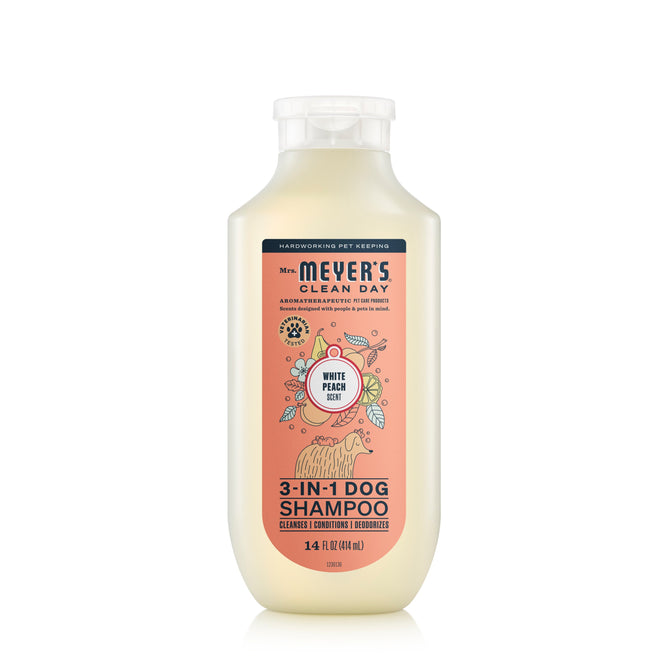 A 14 fl oz (414 ml) white bottle of Mrs. Meyers 3-in-1 Dog Shampoo is pH balanced, veterinarian tested, and features a white peach scent. The label has playful dog and peach illustrations, highlighting cleansing, conditioning, and moisturizing properties for your pets safety.