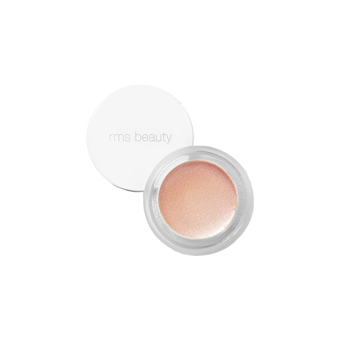 A small round pot of RMS Beauty’s Champagne Rosé Luminizer with a white lid, shown open to reveal a shimmery, champagne-toned cream highlighter for a natural dewy glow. The lid features “rms beauty” in light grey text.