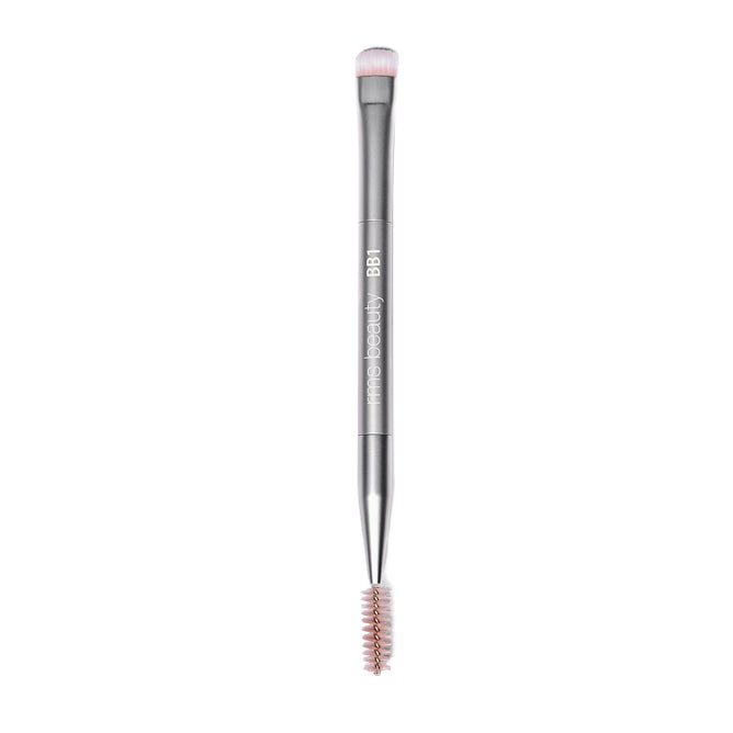 Back2Brow Brush by RMS Beauty is a dual-ended eyebrow tool featuring a round, soft bristle brush for natural brow shaping on one end and a spoolie on the other. The silver handle bears the label “BB1 mine beauty.”.