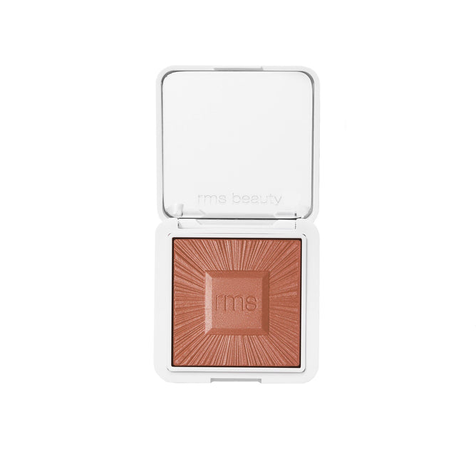 An open, refillable compact of RMS Beauty ReDimension Hydra Bronzer in a warm, shimmery shade features a geometric embossed powder pattern, shown against a white background.