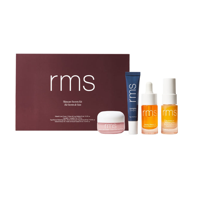 The Skincare Secrets Travel Kit by RMS Beauty includes radiant skin essentials in a dark red RMS box: Lipnights Overnight Lip Mask (pink jar), a blue tube, and two age-defying dropper bottles with orange and white labels.