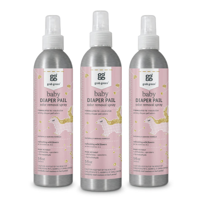 Three bottles of grab green Baby Diaper Pail Odor Removal Spray - Wild Flowers are displayed. They have a pink label with golden leaves and a baby carriage, labeled natural & fragrance-free. Each 5 fl oz bottle contains Zinc ricinoleate for effective odor control.