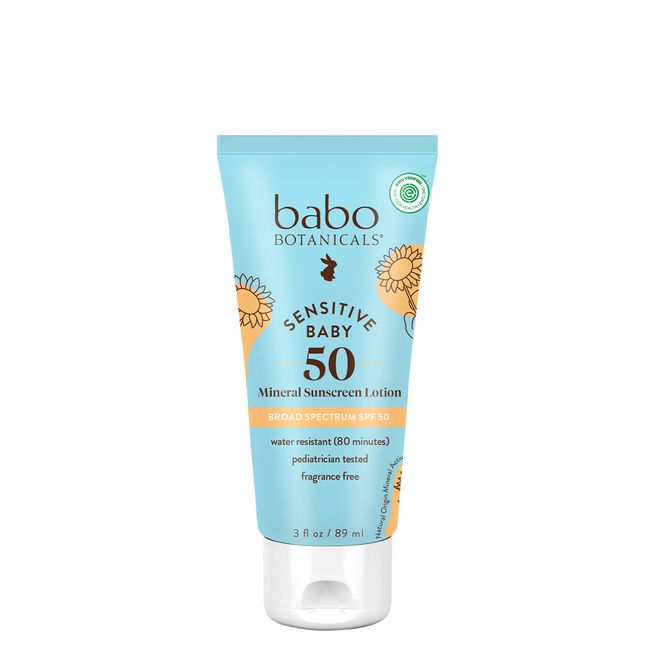 A tube of Babo Botanicals Sensitive Baby Mineral Sunscreen Lotion SPF50, featuring a light blue label with orange accents, is broad spectrum, water resistant, fragrance-free, and pediatrician tested.