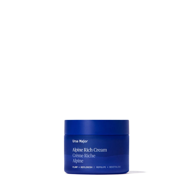 A blue jar of Ursa Major Alpine Rich Cream sits centered on a white background, with white text displaying the product name and emphasizing its moisturizing benefits for skin barrier support.