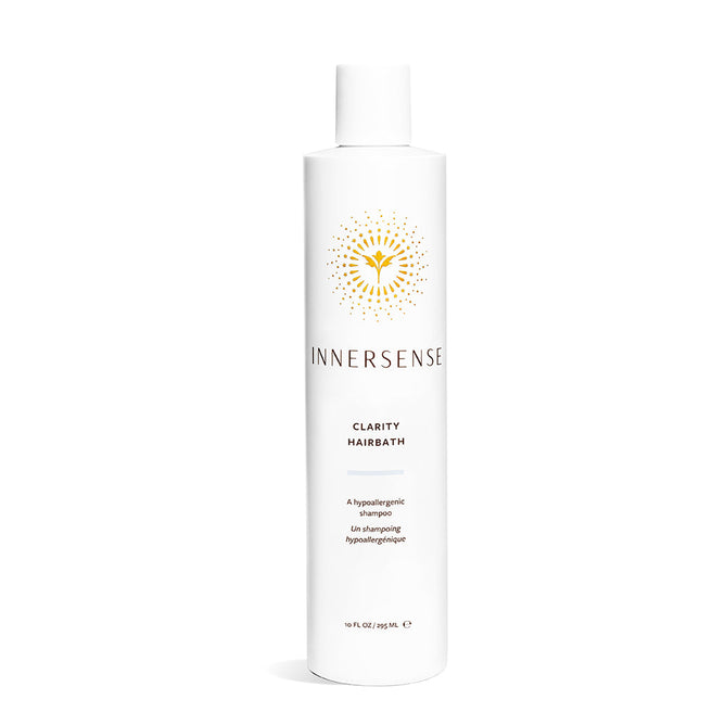 A tall, white bottle of Innersense Organic Beauty Clarity Hairbath shampoo features a hypoallergenic formula for sensitive scalps, with a yellow sunburst design and black text. The bottle has a white cap and sits on a plain white background.