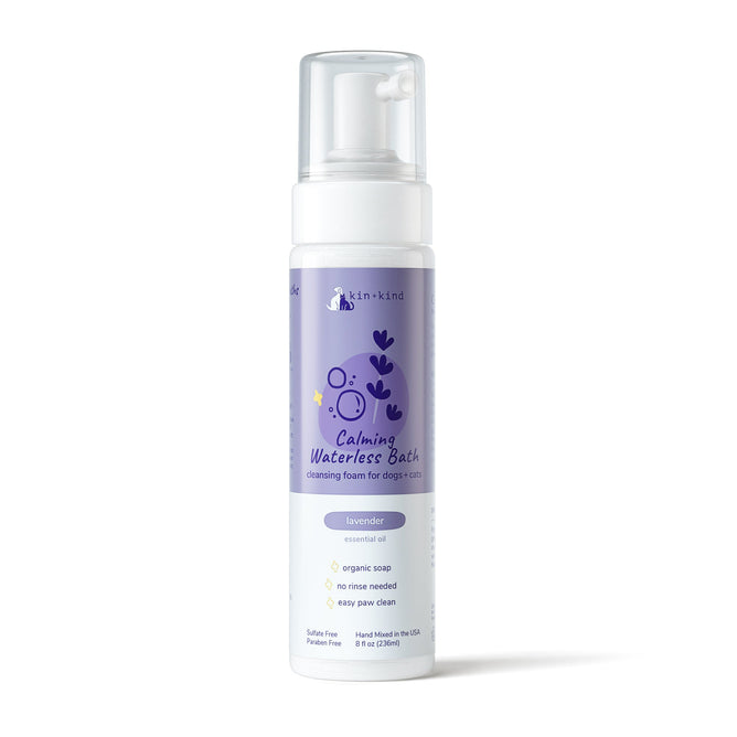 The kin+kind Calming Lavender Waterless Bath for Cats & Dogs in an 8 fl oz purple bottle with pump dispenser emphasizes natural pet care. The label depicts a dog, features organic soap with a lavender scent, requires no rinse, and is ideal for easy paw cleaning. Its sulfate-free and paraben-free.