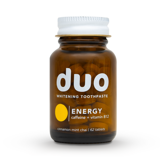 The duo Toothpaste brown glass bottle with a black cap contains 62 Caffeine + B12 Toothpaste Tablets. Its label features a yellow circle stating ENERGY for enhanced absorption, offering a cinnamon mint chai flavor.