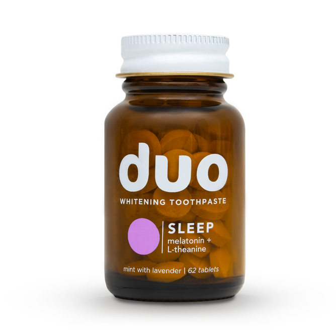 A brown bottle of duo Toothpastes Melatonin Toothpaste Tablets features SLEEP on the label. Enhanced with melatonin and L-theanine, it has a mint lavender flavor and contains 62 tablets. The gold lid matches the purple circle design.