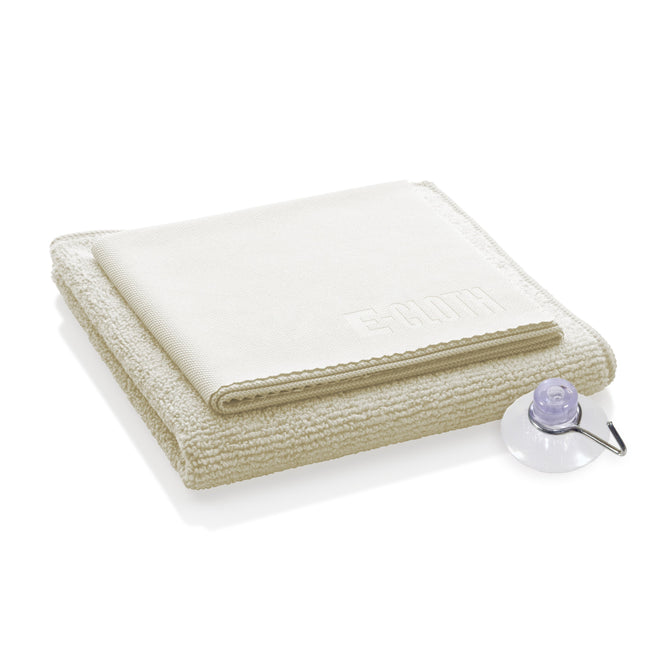 A folded beige microfiber cloth embossed with E-Cloth lies next to a clear suction cup—ideal for your Shower Cleaning Kit.