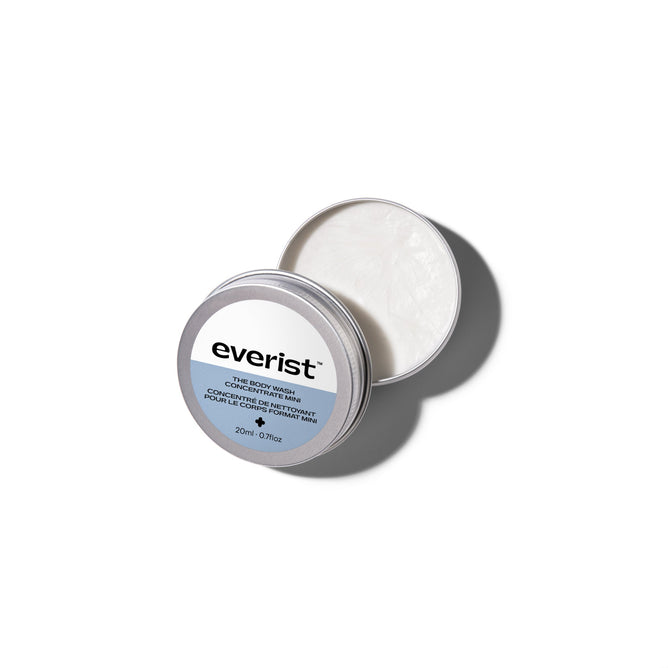 An open round silver tin labeled Everist reveals a creamy white The Body Wash Concentrate Travel Mini by Everist. The tin sits on a white background.