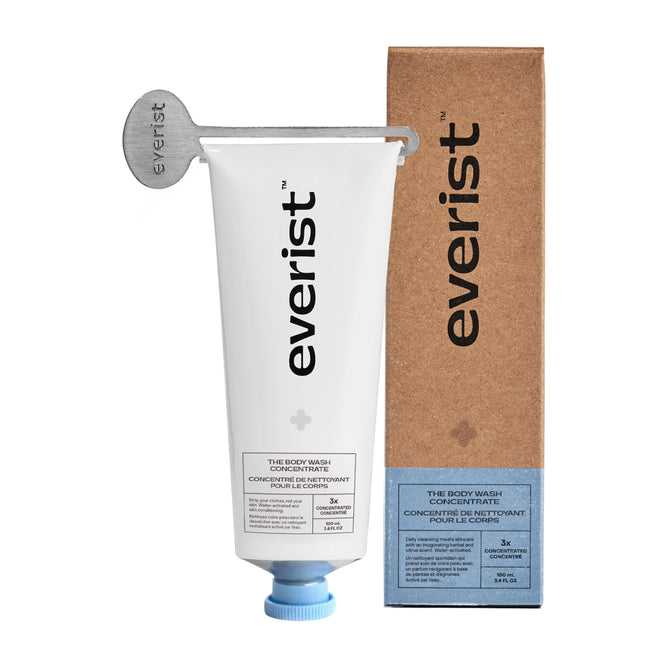 A metal key squeezes a white tube of Everist’s The Body Wash Concentrate, shown beside its brown minimalist box with blue accents—highlighting this plant-based skincare essential.