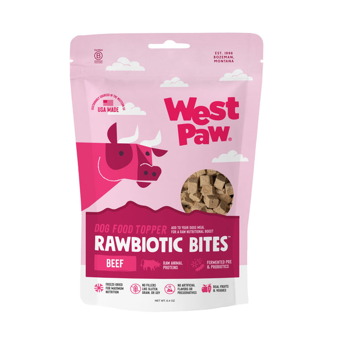 A pink and white bag of West Paws Beef Rawbiotic Bites Dog Food Topper, featuring a cartoon cow and a clear window displaying cube-shaped treats with raw beef protein and fermented probiotics.