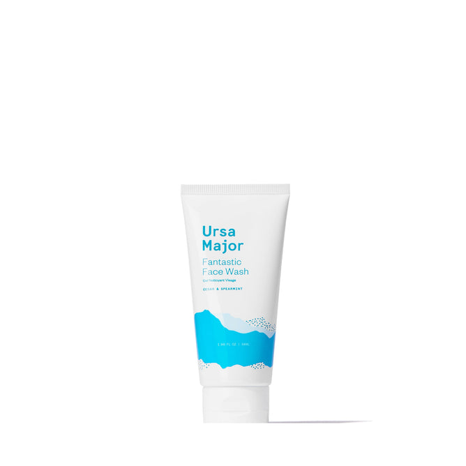 A white tube of Ursa Major Fantastic Face Wash Traveler with blue accents stands upright on a plain white background—an exfoliating daily cleanser ideal for travel.