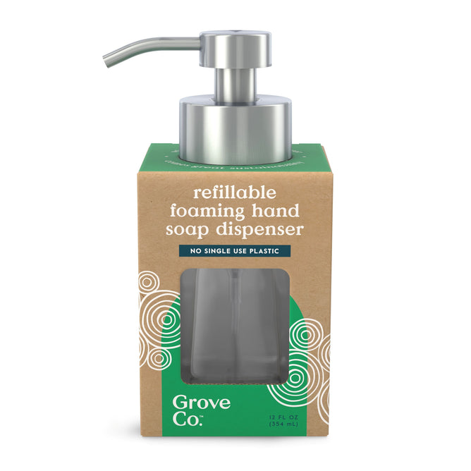 The Grove Co. Reusable Glass Foaming Hand Soap Dispenser is packaged in a brown box with green accents. It includes a metal pump and a transparent window displaying the reusable bottle inside, highlighting its commitment to reducing plastic waste by avoiding single-use plastics.