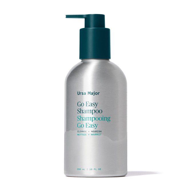 A silver pump bottle of Ursa Major Go Easy Shampoo, featuring teal label text and pump, stands upright against a white background. This shampoo is sulfate-free and suitable for all hair types.
