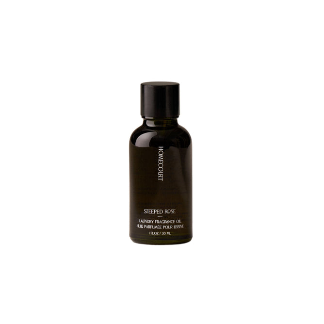 A small dark glass bottle with a black cap labeled Homecourt Laundry Fragrance Oil sits on a plain white background.