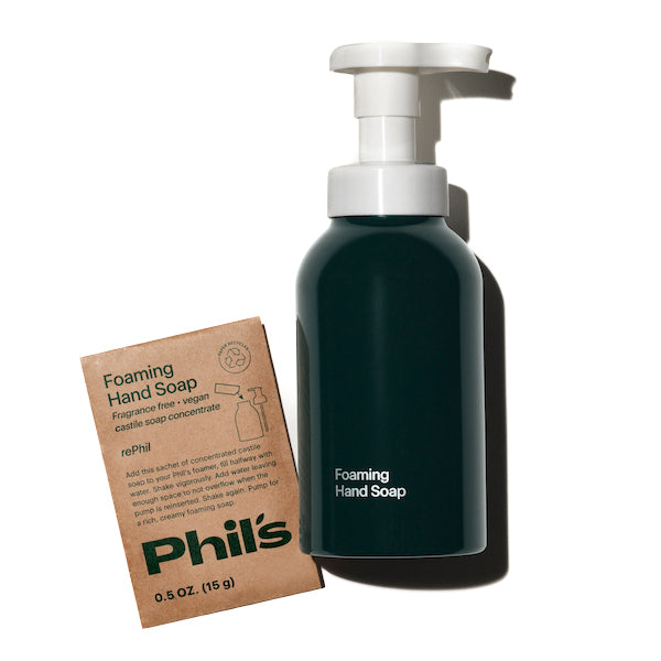 A black Foaming Hand Soap dispenser and a brown refill packet labeled Phil’s, 0.5 OZ (15 g), create the Phils First Phil Hand Soap Starter Kit on a white background.