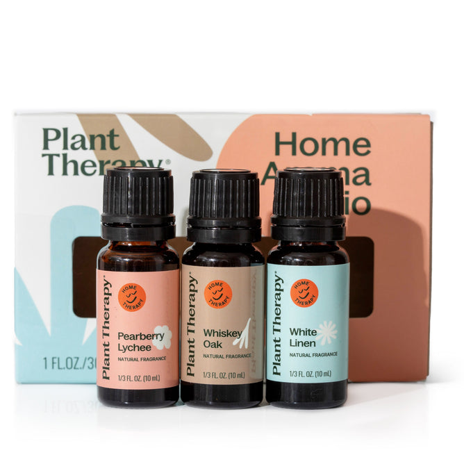 Three essential oil bottles, Pearberry Lychee, Whiskey Oak, and White Linen, rest elegantly in front of a pastel Plant Therapy Chasing Sunshine Essential Oil Blend Set box, offering an uplifting and grounding fragrance experience.