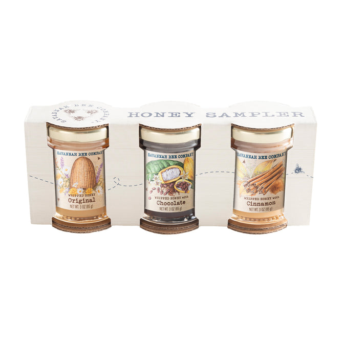 The Savannah Bee Company Whipped Honey Sampler includes three 3oz jars—Original, Chocolate, and Cinnamon—each with illustrated labels, packaged in a white display box.
