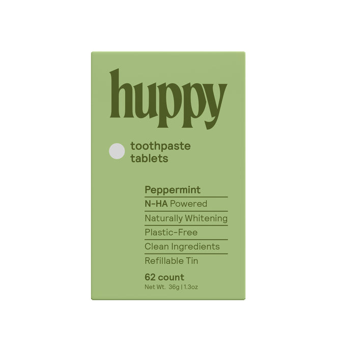 A green box labeled Huppy Toothpaste Tablets with Tin in peppermint, featuring phrases like N-HA Powered, Sustainable Oral Care, Naturally Whitens, Plastic-Free, Clean Ingredients, and Refillable Tin; contains 62 tablets.