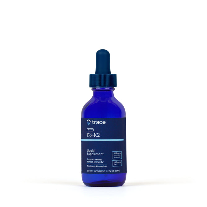 A blue glass dropper bottle labeled Ionic D3 + K2 Drops by Trace Minerals, with a dark blue dropper cap and featuring bioavailable vitamins D3 and K2, is photographed against a plain white background.