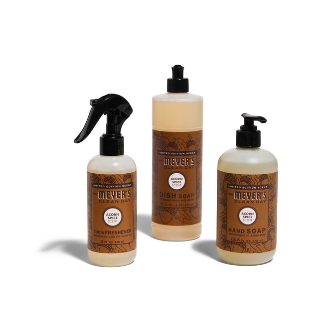 The Mrs. Meyers Harvest Home Helpers Set in Acorn Spice includes a room spray, dish soap, and hand soap with pumps, all in decorative brown and beige bottles.