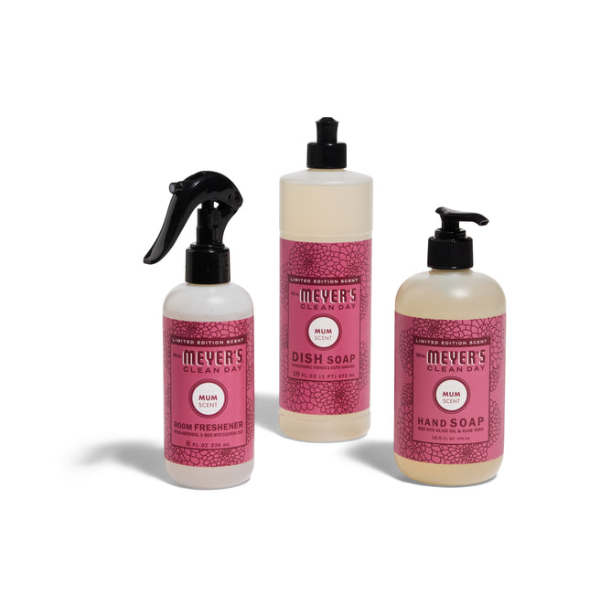 The Mrs. Meyers Harvest Home Helpers Set - Mum includes a room freshener spray, dish soap with pump, and hand soap with pump, all in clear bottles with pink labels.