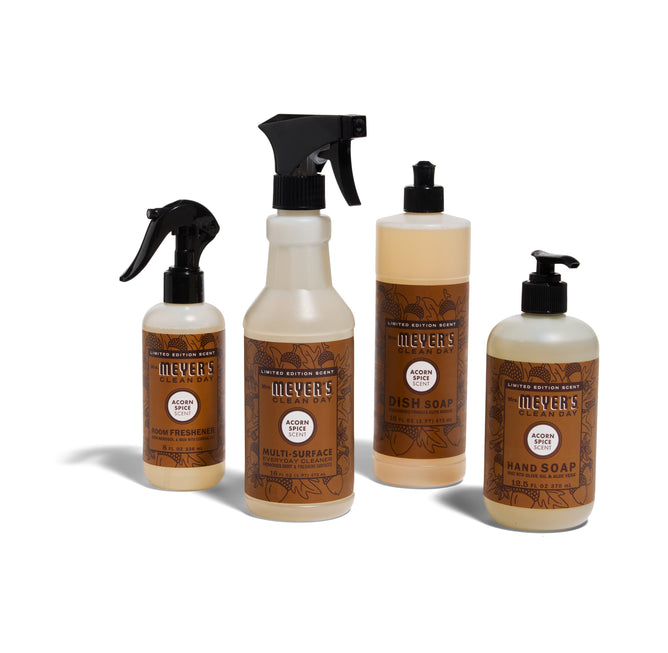 The Mrs. Meyers Autumn Breeze Cleaning Set - Acorn Spice includes room spray, multi-surface cleaner, dish soap with pump, and hand soap with pump in beige bottles with brown and orange labels.