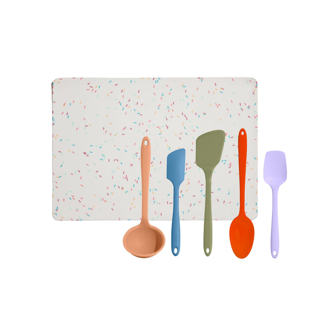 The GIR 5-Piece Ultimate Tool Set includes a peach ladle, blue spatula, green spatula, red spoon, and lavender spatula. All items are heat-resistant silicone. A white cutting board with a colorful sprinkles design is included as a free gift and is neatly displayed on a white background.