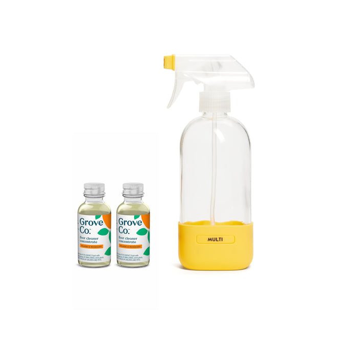 Two Grove Collaborative Floor Cleaner Starter Set bottles with green labels are placed beside a reusable spray bottle featuring a yellow base and white nozzle; the cleaners on the left, spray bottle on the right, set against a pristine white backdrop.