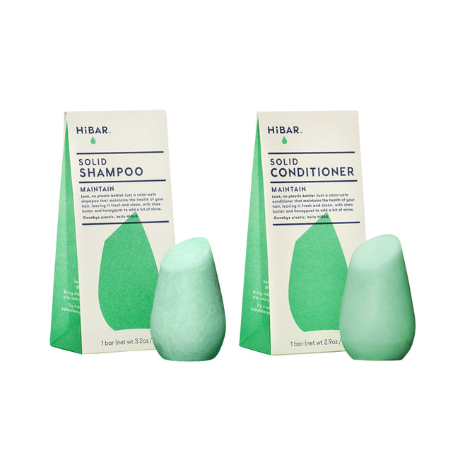 Two green HiBAR Maintain Haircare Set bars—shampoo and conditioner—stand side by side before matching green and white packaging, displaying their signature teardrop shape and eco-friendly design.