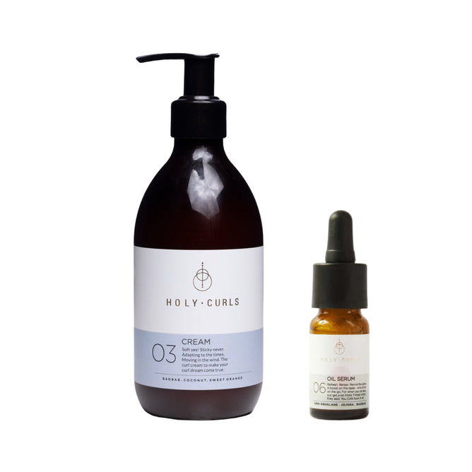 The Holy Curls Cream + free gift set includes a black pump bottle labeled 03 Curl Cream with shea butter and a small dropper bottle labeled 06 Oil Serum featuring baobab oil. The bottles have a consistent color scheme, with the cream sporting a white label.