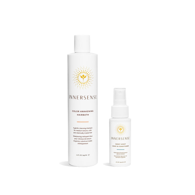 Two white bottles of Innersense Organic Beauty products are shown on a white background. The bigger bottle is the Color Awakening Hairbath + free gift, a color-safe shampoo with coconut and pumpkin seed oils, and the smaller is Sweet Spirit Leave In Conditioner. Both have a sunburst logo.