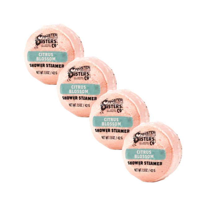 Four round, peach-colored Citrus Blossom Shower Steamers from Grove Collaborative are arranged diagonally on a white background.
