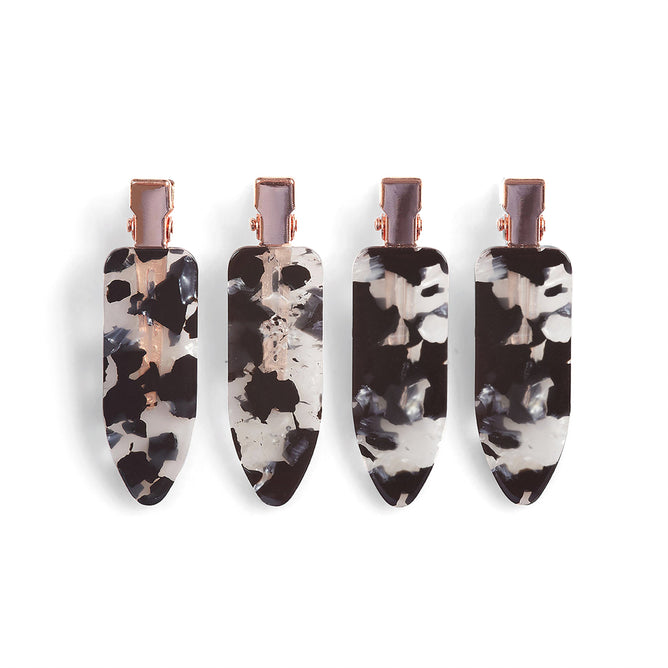 A set of four teardrop-shaped Eco-Friendly Creaseless Clips by Kitsch, featuring metal clasps and a tortoiseshell pattern with black, white, and gray swirls, elegantly holds hair without harming the environment, using materials sourced responsibly.