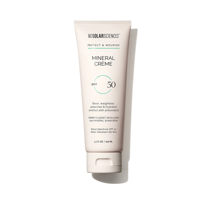 An off-white tube of MDSolarSciences Mineral Crème SPF 50 sunscreen, displayed on a white background, features black and green text and highlights its sheer, weightless makeup primer feel with broad spectrum protection.
