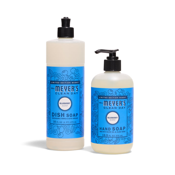 Two bottles of Mrs. Meyers Sunsational Sink Essentials - Blueberry set: dish soap with a flip cap and hand soap with a pump, both featuring blue labels with illustrated blueberries.