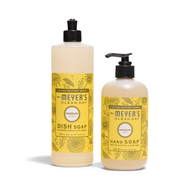 Two yellow bottles of Mrs. Meyers Sunsational Sink Essentials - Dandelion: a tall dish soap with flip cap and a shorter hand soap with pump, both labeled Dandelion and decorated with dandelion illustrations.