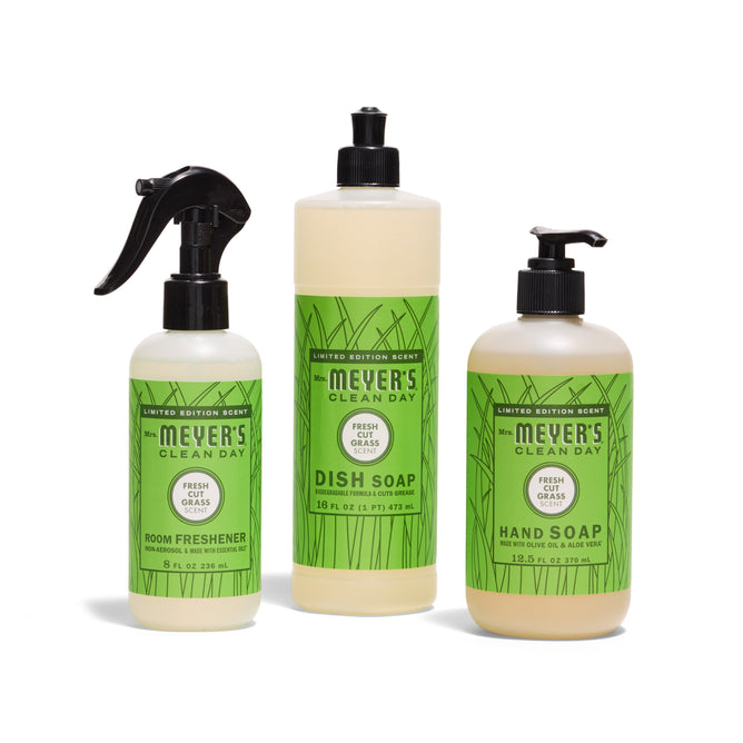 Three Mrs. Meyer’s Scents & Sun Essentials - Fresh Cut Grass products—room freshener spray, dish soap with pump, and hand soap with pump—are displayed against a white background.