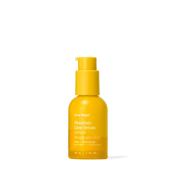 A bright yellow bottle with a pump, labeled Ursa Major Mountain Glow Serum, stands upright on a white background. This 30ml serum nourishes skin and reduces the appearance of wrinkles.