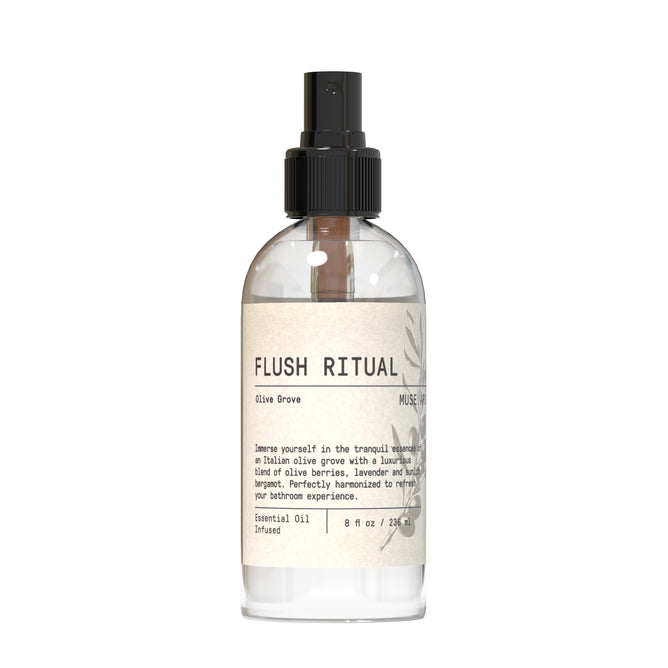 A clear spray bottle labeled Muse Apothecary Toilet Spray - Olive Collection with a black pump, featuring a minimalist beige label describing notes of olive, lavender, bergamot, olive laurels, and Tuscan thyme.