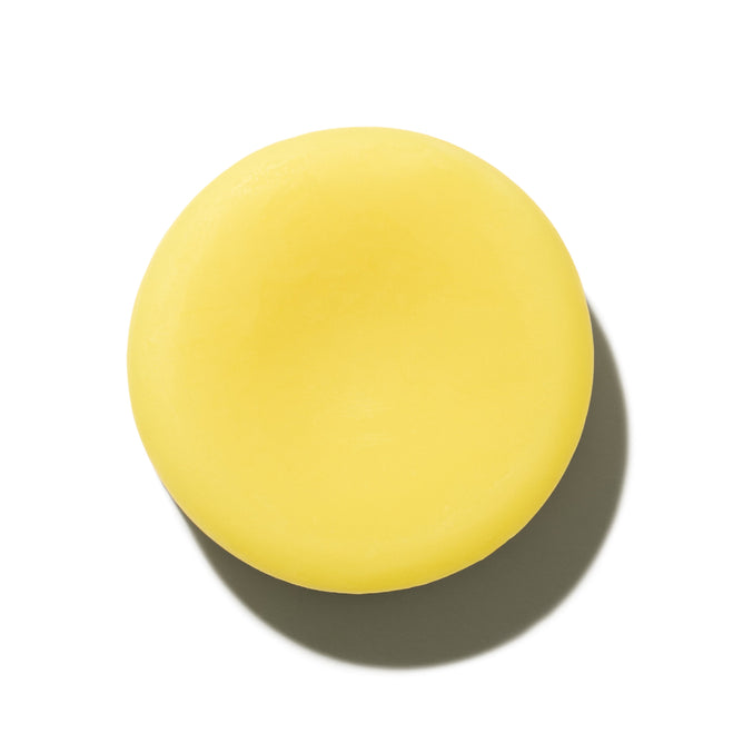 A round, solid yellow Sorrento Conditioner Bar by NOT!CE Hair Co is pictured on a white background with a shadow to the right—a perfect plastic-free hair care solution.