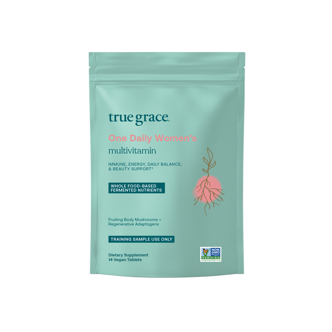 A teal packet labeled True Grace One Daily Womens Multivitamin - Sample offers immune support, energy, daily balance, and beauty benefits. It contains 14 vegan tablets with whole-food-based fermented nutrients and features a plant illustration for a natural touch.
