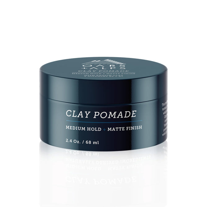 A dark teal Oars + Alps Clay Pomade container, labeled Medium Hold + Matte Finish, 2.4 oz / 68 ml, is displayed on a white background—ideal for matte hold and strengthening hair.