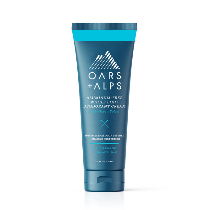 A blue tube of Oars + Alps Aluminum-Free Whole Body Cream Deodorant stands upright on a white background, featuring white and light blue text and graphics. This deodorant uses natural starches for effective, whole-body odor protection.