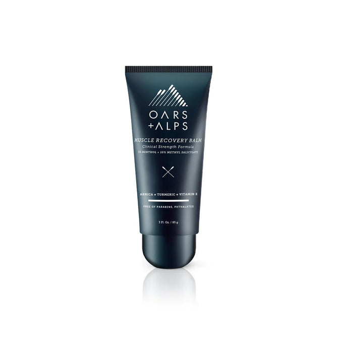 Oars + Alps Muscle Recovery Balm is an anti-inflammatory balm with arnica, turmeric, and vitamin E. The dark blue tube stands upright on a white background and is ideal for soothing sore muscles.