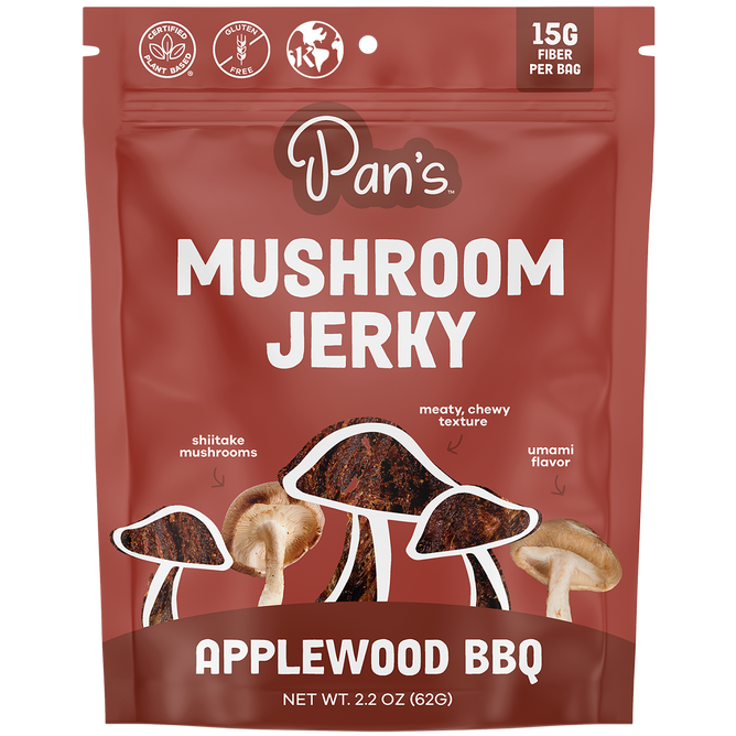 The vibrant red package of Pans Applewood BBQ Mushroom Jerky highlights 15G Fiber Per Bag, Vegan, Gluten Free, and Kosher symbols, featuring illustrations of shiitake mushrooms and textured jerky strips, reflecting its plant-based, savory flavor.