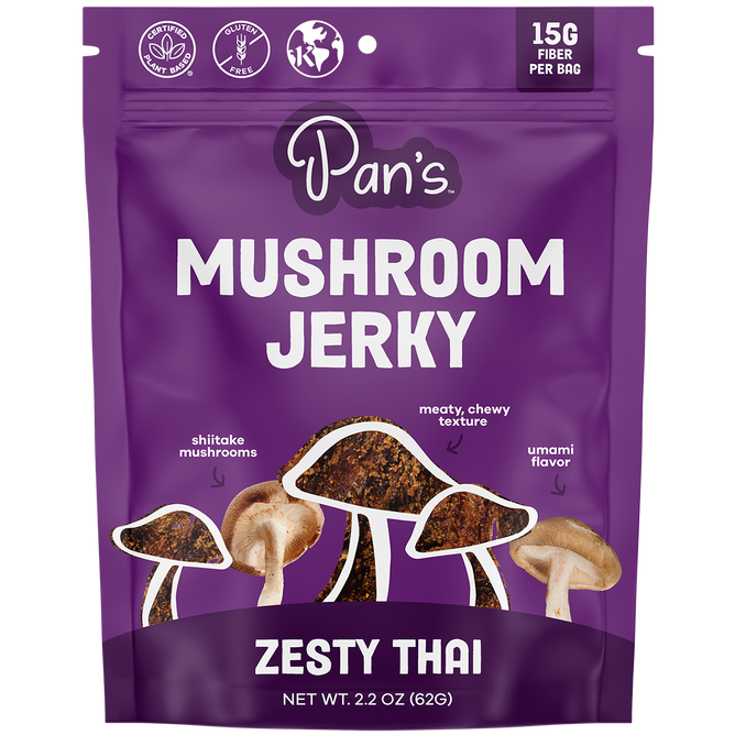 Pans Zesty Thai Mushroom Jerky, a vibrant purple bag, is ideal for vegan snack seekers. This gluten-free treat contains 15G fiber per bag and features images of shiitake mushrooms emphasizing its meaty, chewy texture with an umami flavor. Net wt. 2.2 oz (62g).